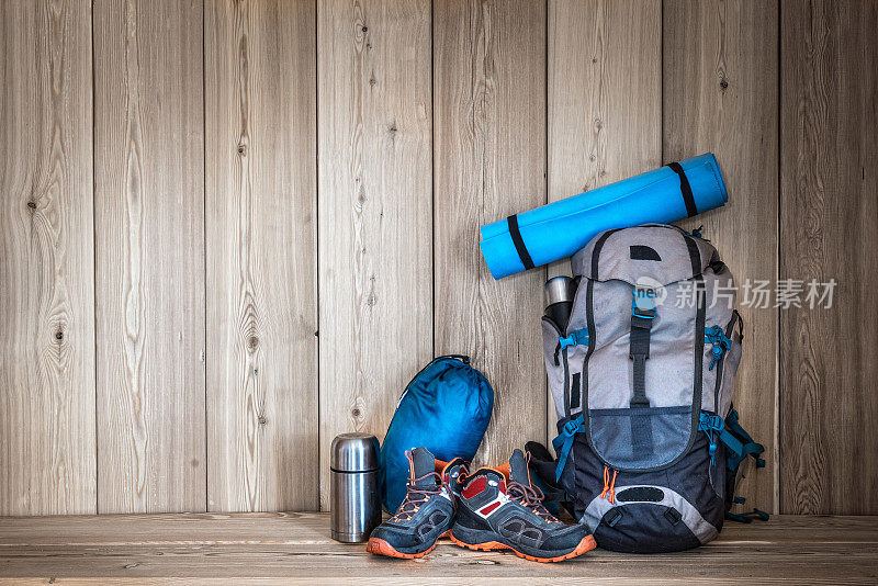 露营装备，鞋子，背包和一个保温瓶，木质背景