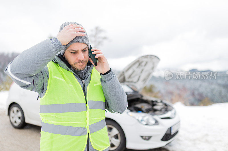 忧心忡忡的男人用智能手机寻求帮助。汽车抛锚的背景。冬天的季节。
