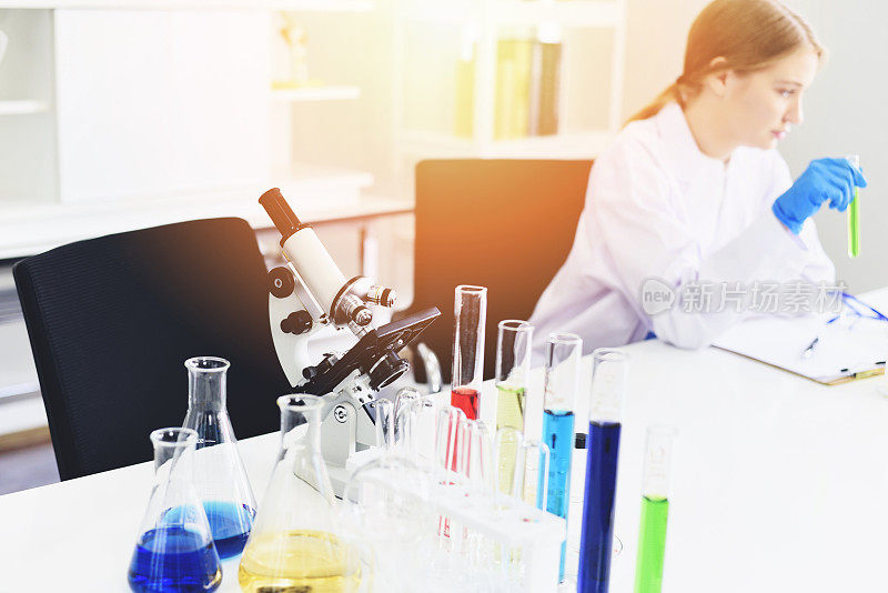 年轻的女科学家做一些研究工作，在现代实验室进行实验和显微镜-科学家在实验室生物化学、遗传学、法医学、微生物学和试管女医生