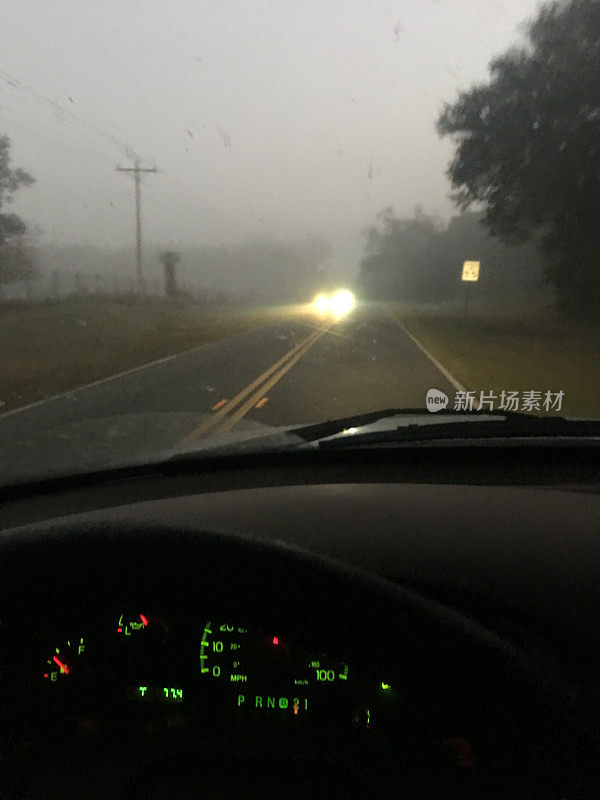 在黎明前的大雾中行驶，迎面而来的汽车前灯被分散开来