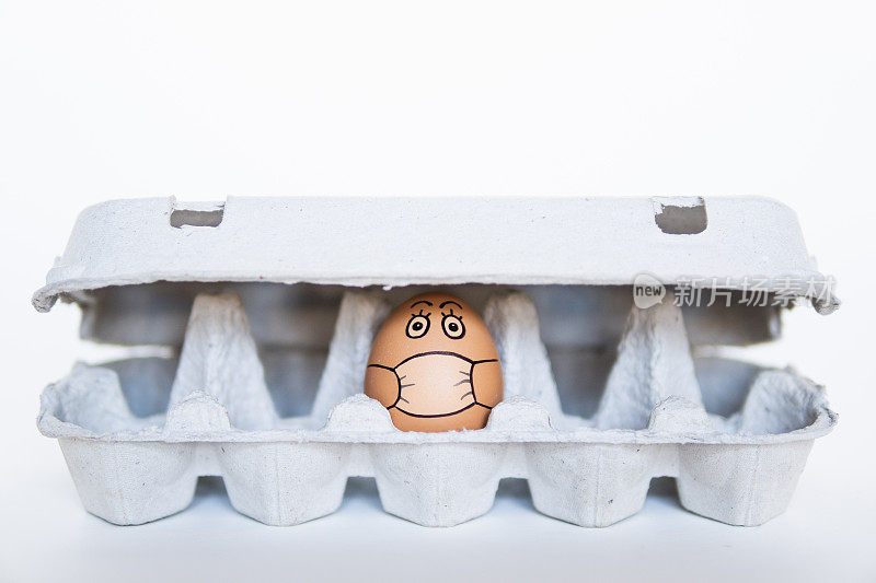 鸡蛋在托盘上涂鸦脸戴着医用口罩。冠状病毒隔离期间居家的概念形象