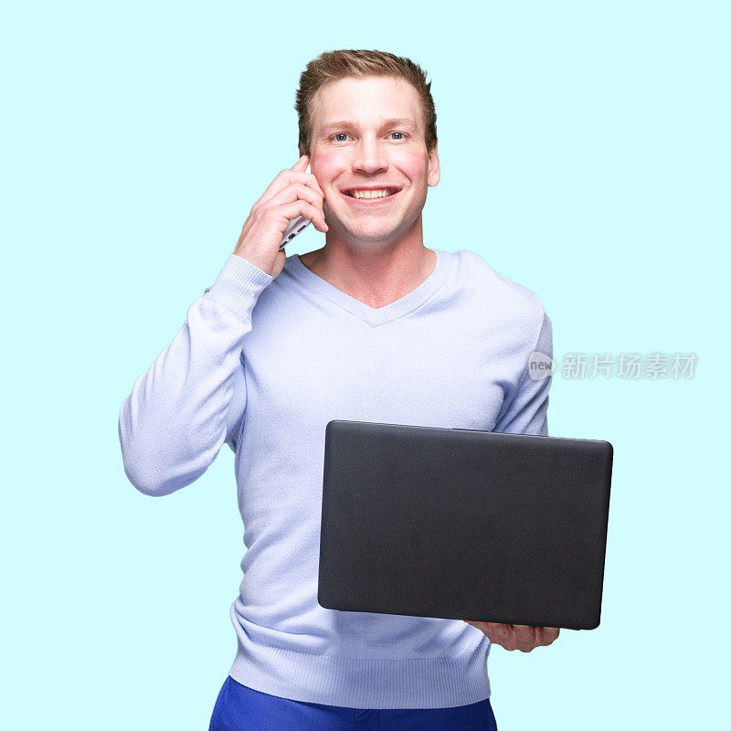 白人年轻男性站在有色背景前穿着v领，使用笔记本电脑
