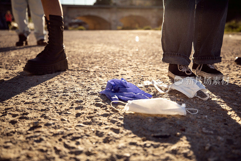 一群青少年丢弃在街上的一次性外科口罩和防护手套