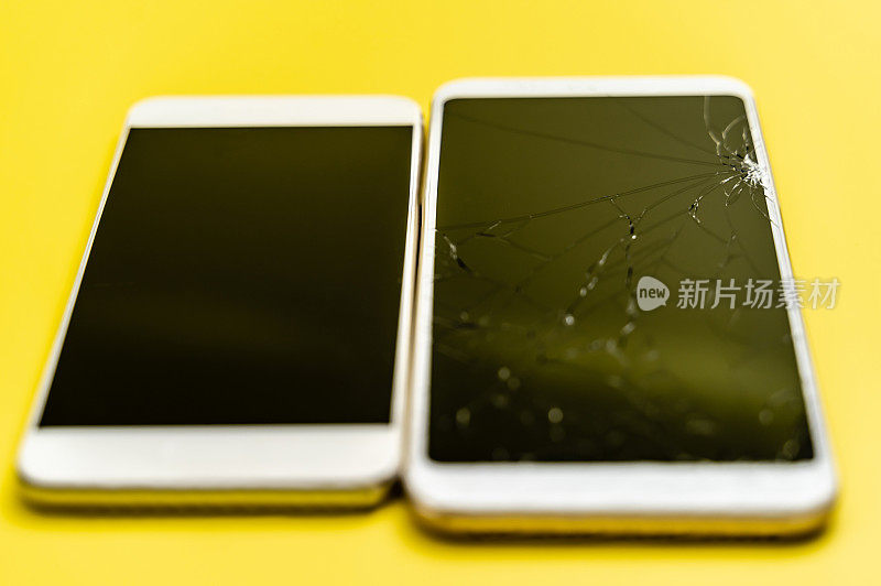 两部智能手机，一部是破屏幕，黄色背景