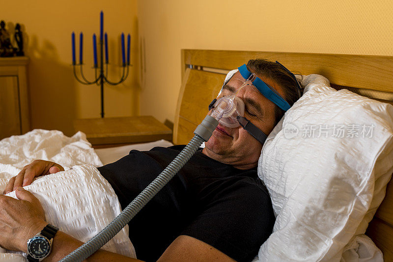由于阻塞性睡眠呼吸暂停，男子戴着呼吸面罩睡觉
