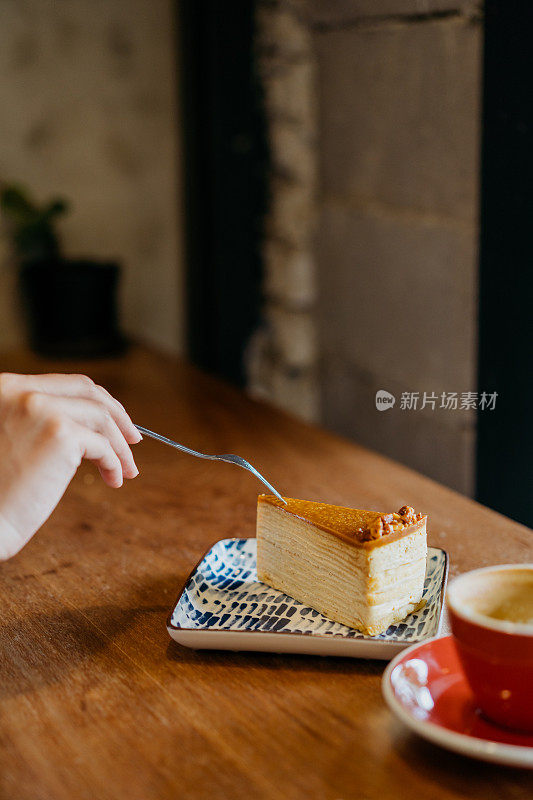 一个女人在咖啡馆用叉子吃薄饼