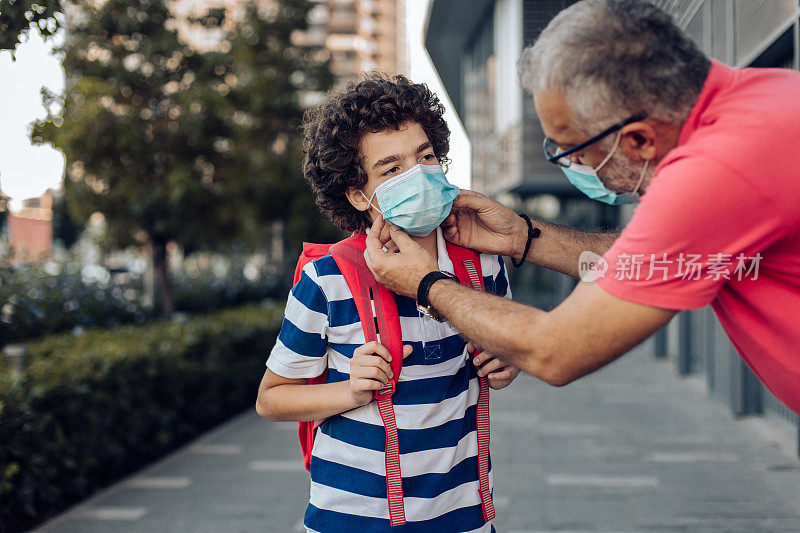 一个男人正在为他的学生调整口罩