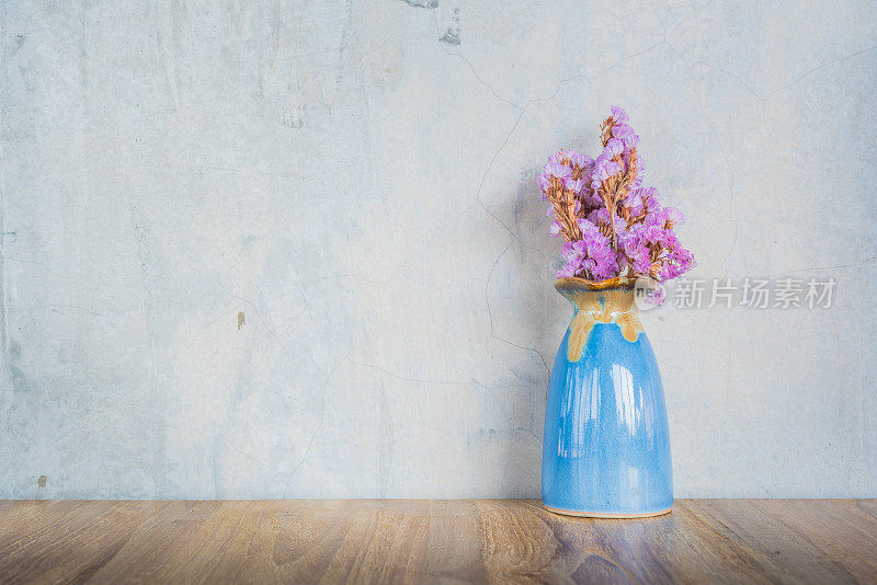 木桌上蓝色花瓶里插着粉红色的花
