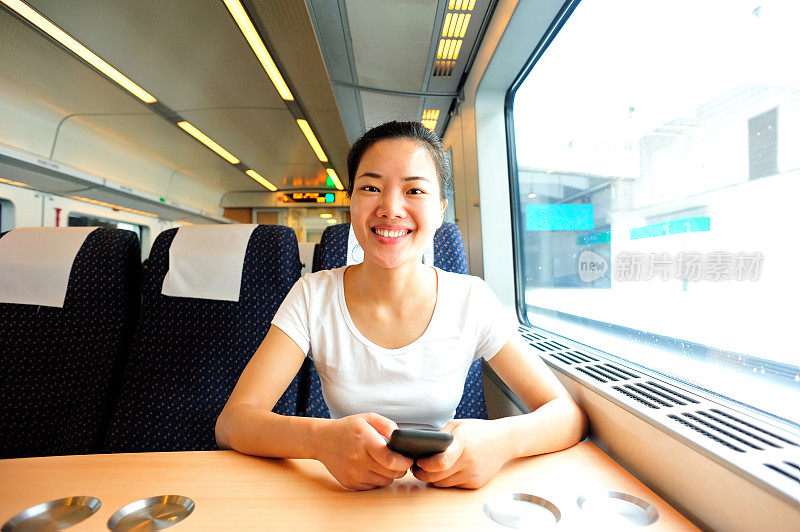 年轻女子在高铁上使用智能手机