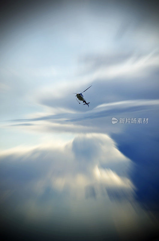 透过云层，一架直升飞机和蔚蓝的天空——变焦应用