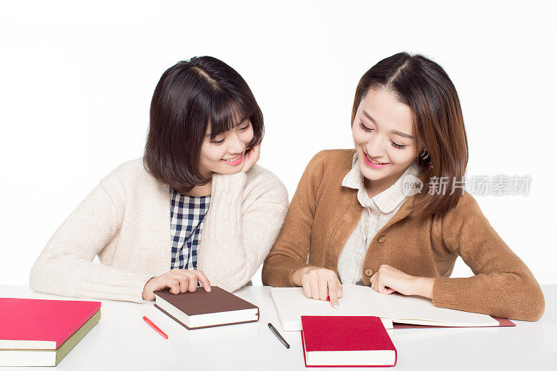 两个美丽的中国女人坐在教室里，快乐地学习