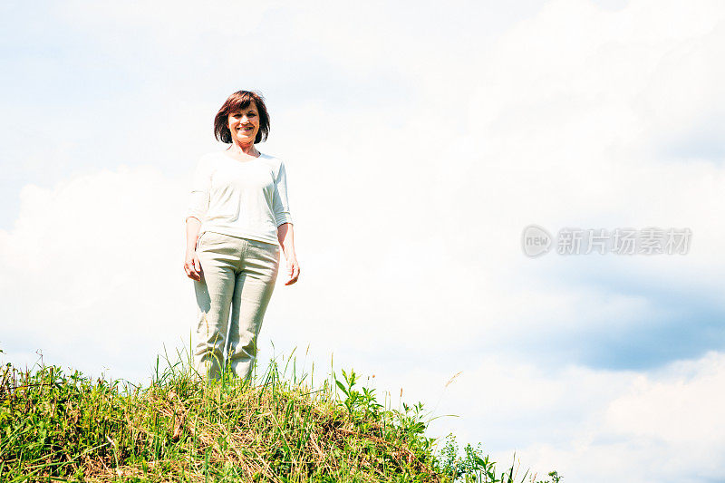 老妇人站在阴云密布的夏日天空前