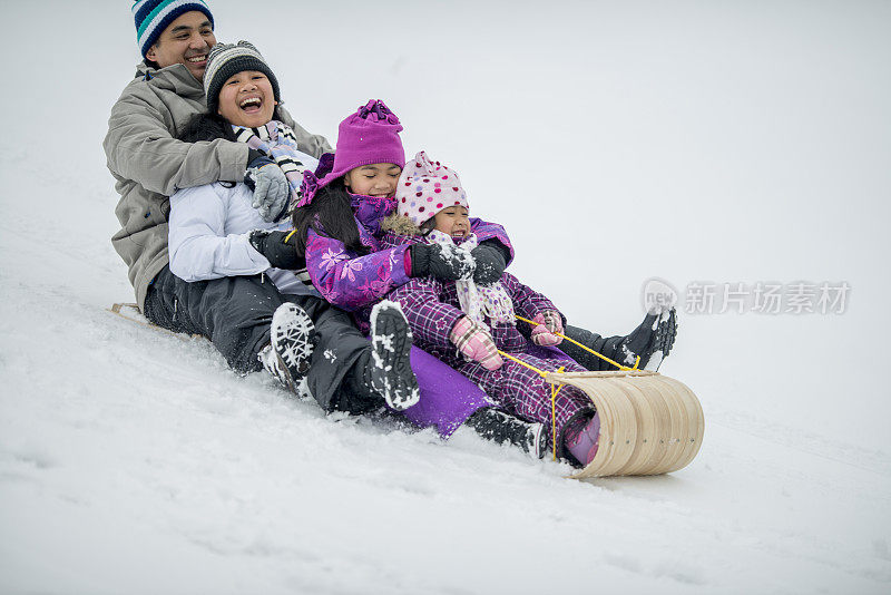 一家人骑着雪橇滑下雪山