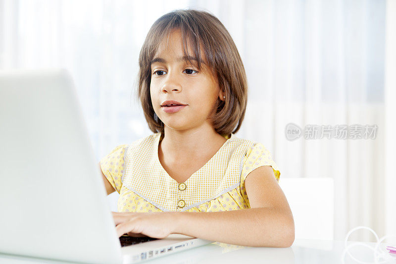 小女孩在用笔记本电脑工作。