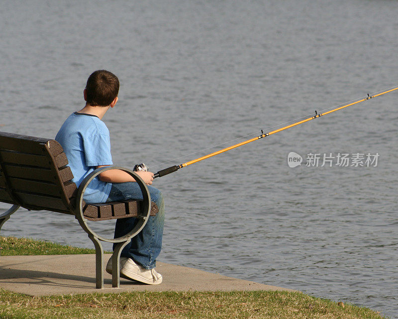 男孩在公园长椅上钓鱼
