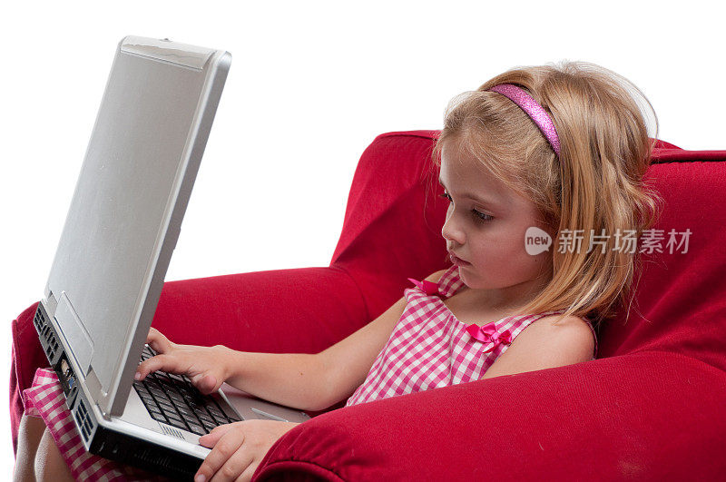 红椅子上的女孩在用笔记本电脑工作。