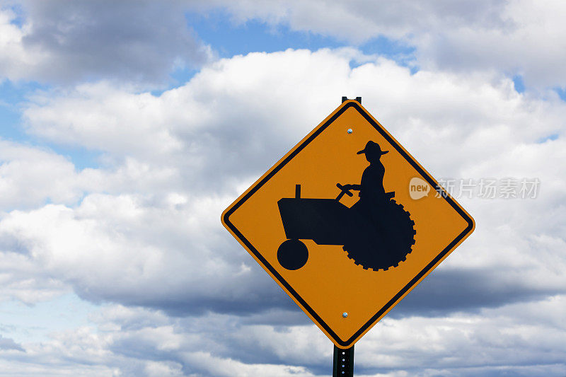 带有多云背景的路边拖拉机过马路标志