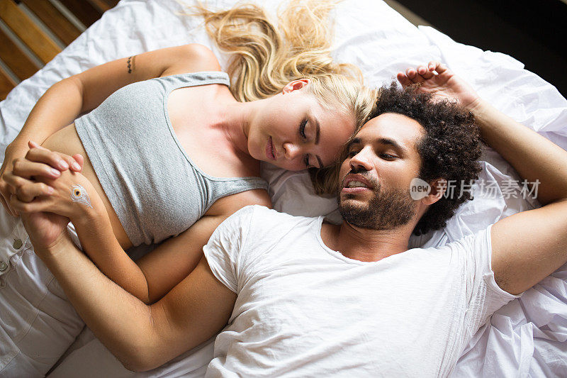轻松的年轻夫妇聊天和躺在床上