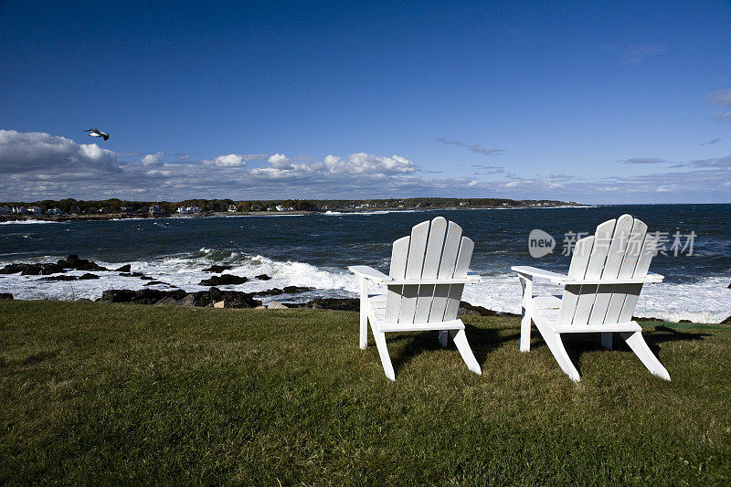 海边沙滩上的两把木椅