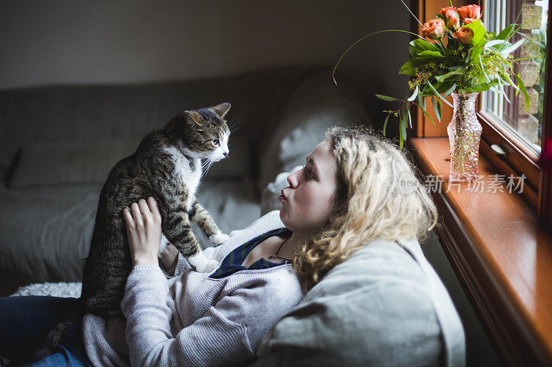 一个女孩和一只猫一起坐在沙发上