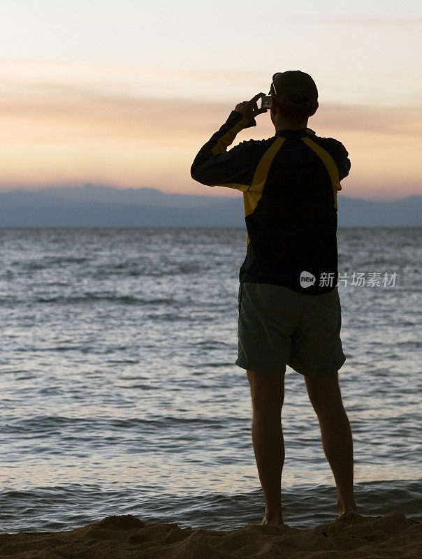 年轻男子在日落时拍照，在太浩湖，人像相框