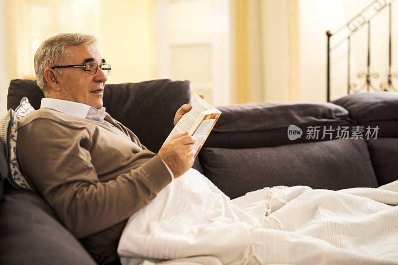 放松的老人在客厅看书。