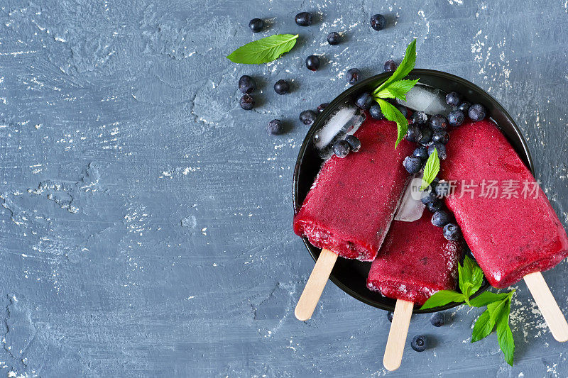 浆果冰淇淋，蓝莓和薄荷在混凝土蓝色背景。夏天冷甜点。