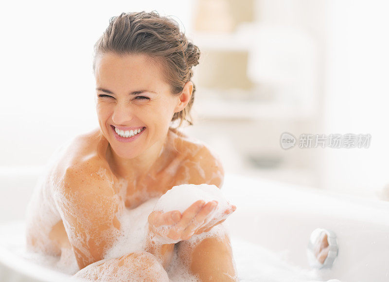 年轻女子在浴缸里玩泡沫