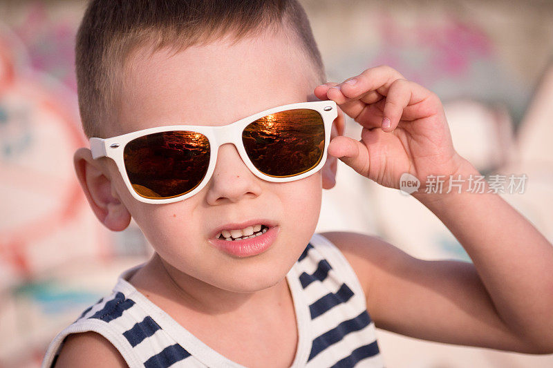 漂亮的小男孩戴着时髦的太阳镜在夏天
