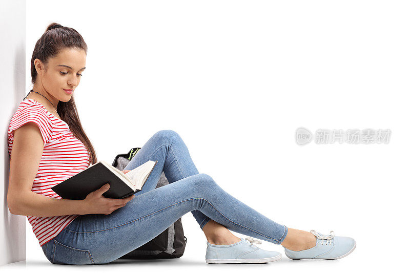 一个十几岁的学生靠在墙上看书