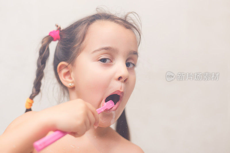小女孩在白色背景上刷牙