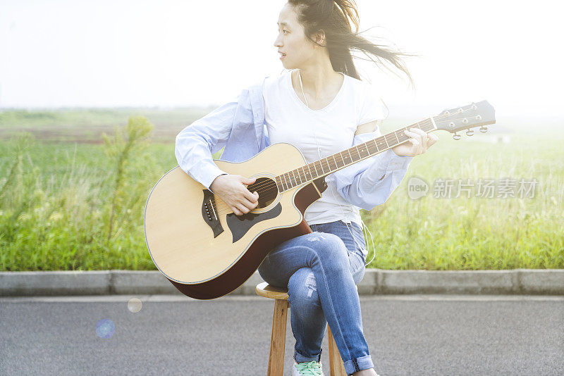 在草地上弹吉他的时尚女人
