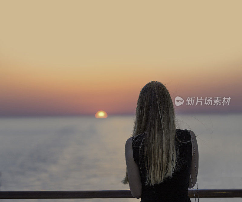 一个年轻女子在夕阳下眺望大海