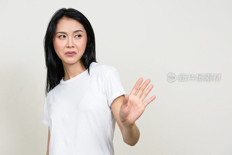 年轻美丽的亚洲女人穿着白色衬衫对抗白色背景