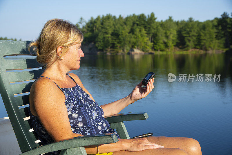 一个成熟的糖尿病女性在湖边的码头上测试她的血糖。