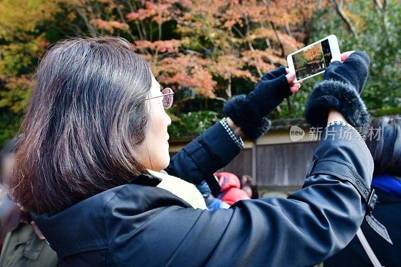 一名日本妇女在京都雅色的秋叶下自拍