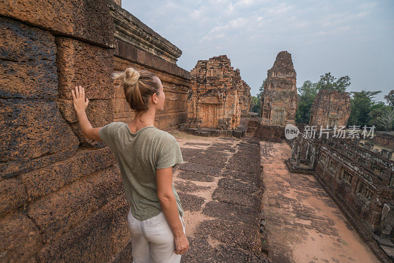 年轻女子在柬埔寨古庙顶上凝视日落