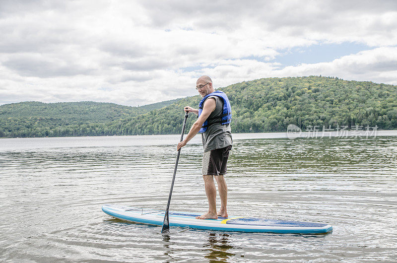 夏日，一名男子站在湖上的桨板上