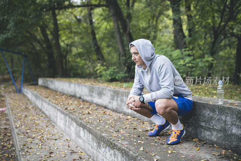 户外训练后，年轻的运动员坐在公园的楼梯上休息。健身、运动、生活理念