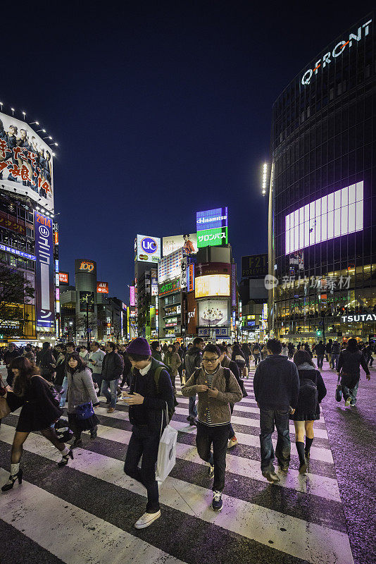 在日本新宿，熙熙攘攘的人群穿过灯火通明的街道