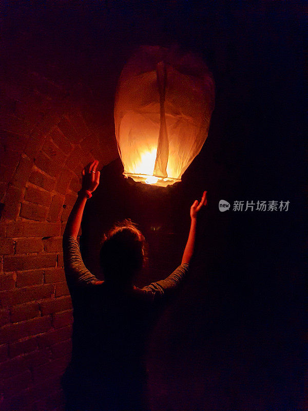 北京——一个女人在一堵砖墙旁边释放一个气球。气球正慢慢地飘离那个人
