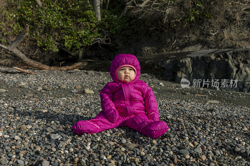 美丽的一岁小女孩独自坐在户外的海滩岩石上