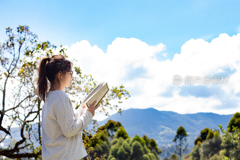 美丽的女人读着一本书，清晨的天空一片蔚蓝