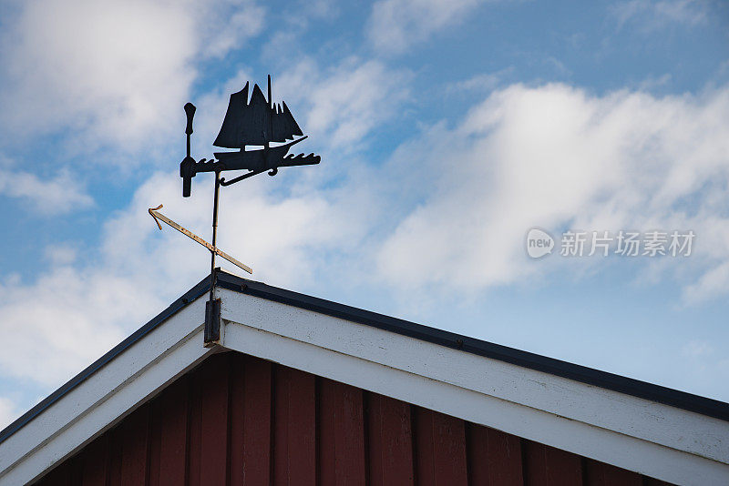 斯堪的纳维亚避暑别墅的斜屋顶上有一个金属风向标，类似于一艘古代北欧海盗帆船或三桅帆船