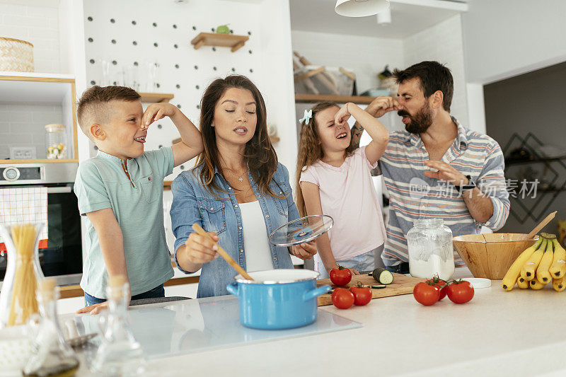 年轻幸福的家庭在厨房里玩得开心。库存图片