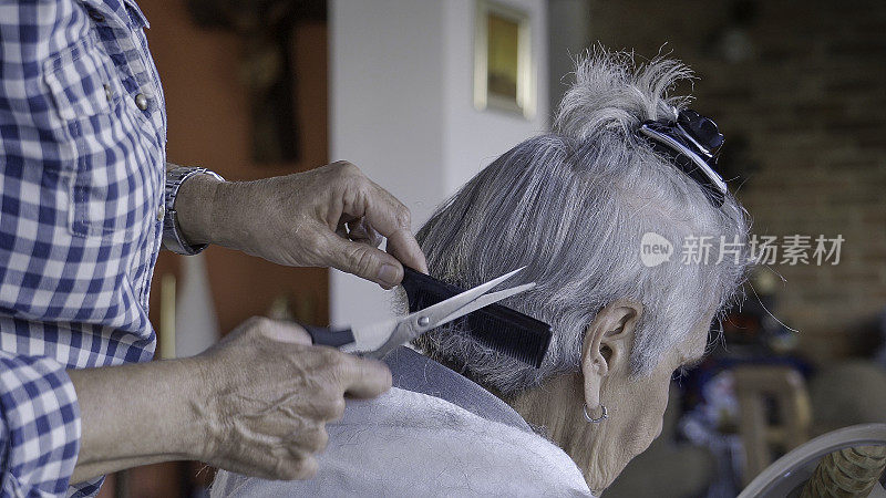 在冠状病毒隔离期间，一名妇女在家用剪刀剪头发