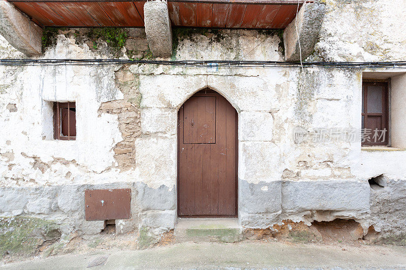 这是一所古老的房子，入口处有一个拱门，一扇木门上嵌有一扇窗户，位于普拉森西亚的奥利瓦。