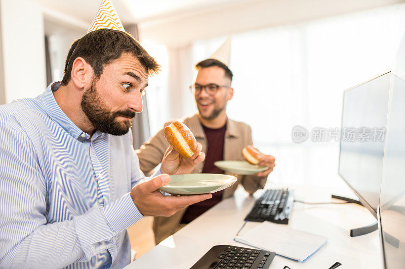 两个友好的生意伙伴在办公室庆祝生日。