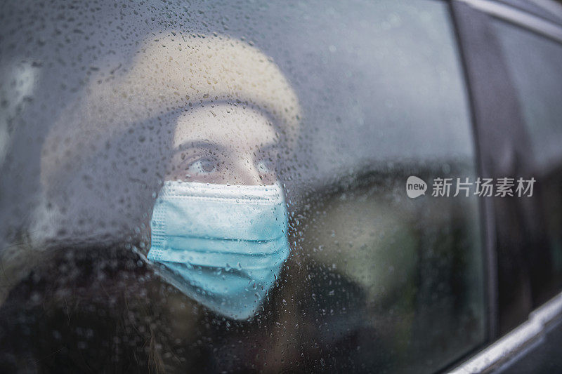 下雨天在车里戴着面具的悲伤年轻女子