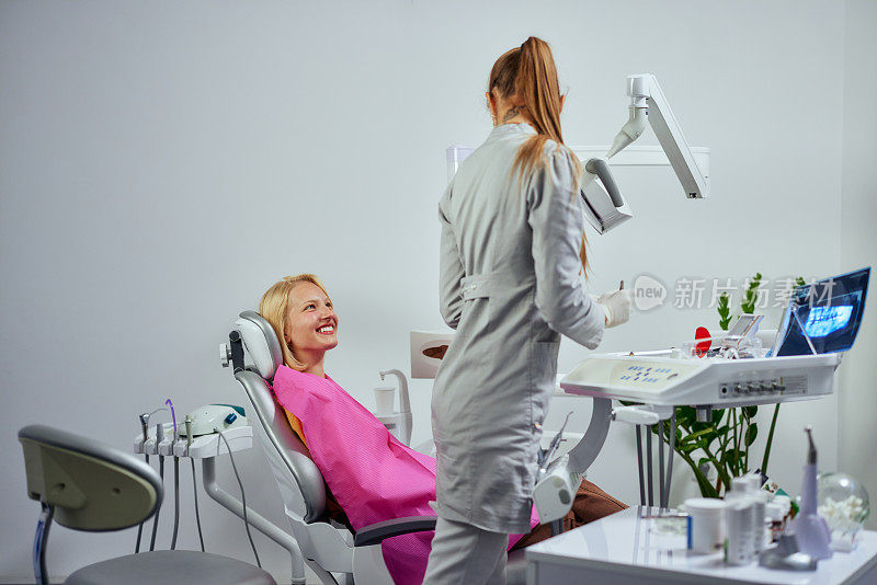 女病人坐在牙科椅上和她的牙医交谈